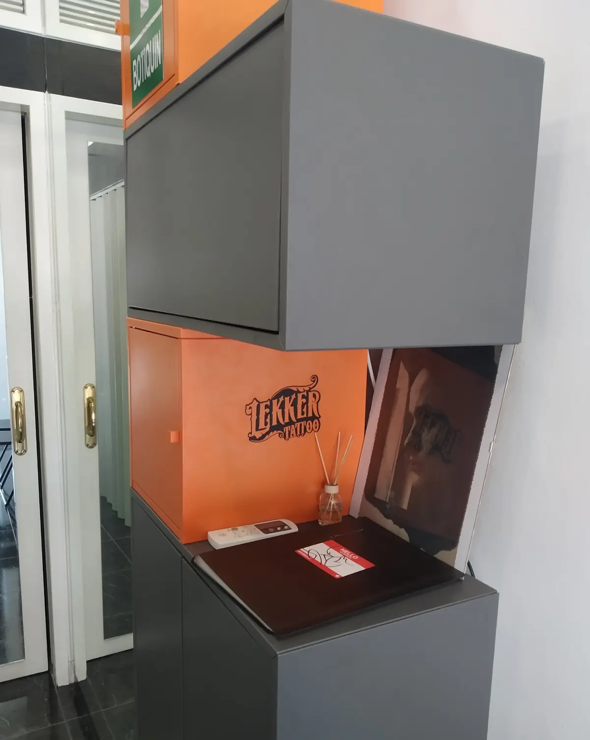 Recepción del estudio con mueble naranja y el logotipo de Lekker Tattoo
