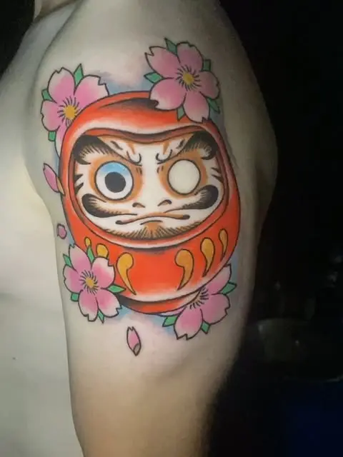 Daruma con flor de cerezo en el brazo